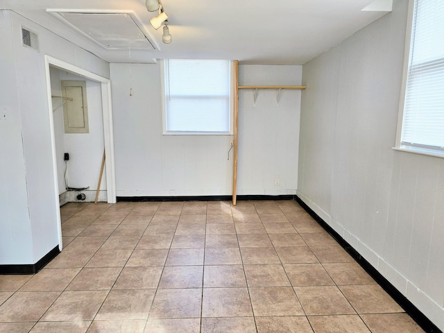 unfurnished room with electric panel, a wealth of natural light, light tile patterned floors, and track lighting