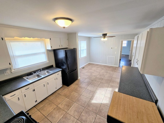 kitchen featuring white cabinets, black refrigerator, crown molding, sink, and light tile patterned floors