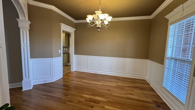 unfurnished dining area with a notable chandelier, crown molding, and dark wood-type flooring