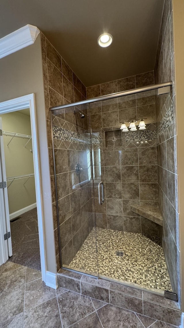 bathroom featuring tile patterned floors, a shower with door, and ornamental molding