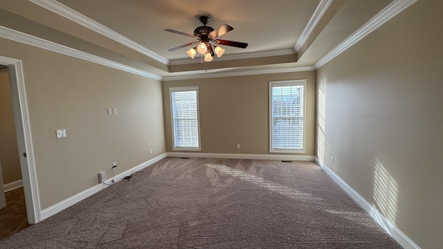 carpeted spare room featuring a raised ceiling, a wealth of natural light, and ornamental molding