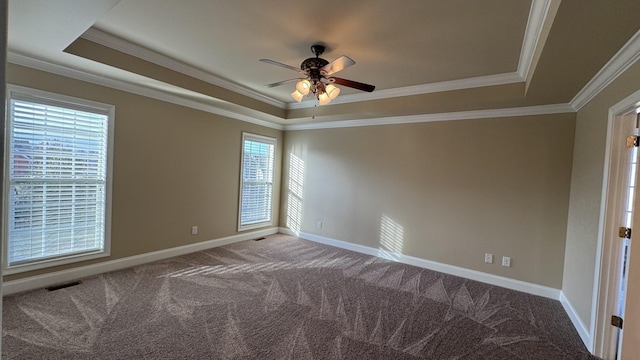 empty room with a raised ceiling, carpet floors, and ornamental molding