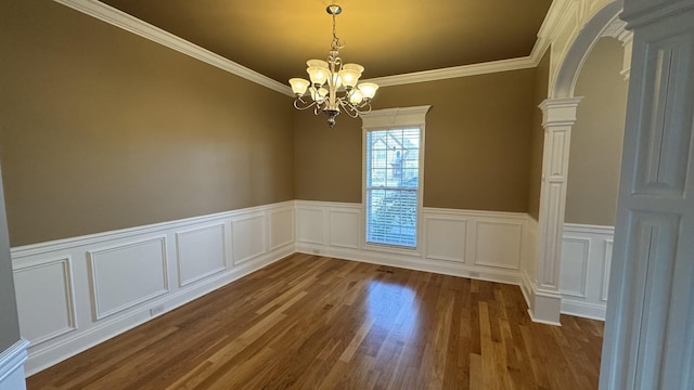 empty room with dark wood-type flooring, an inviting chandelier, and ornamental molding