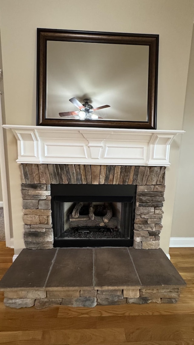 room details with ceiling fan, wood-type flooring, and a fireplace