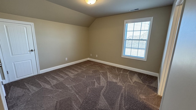 bonus room with dark colored carpet and vaulted ceiling