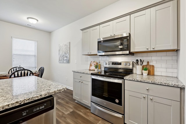 kitchen with decorative backsplash, light stone counters, and appliances with stainless steel finishes