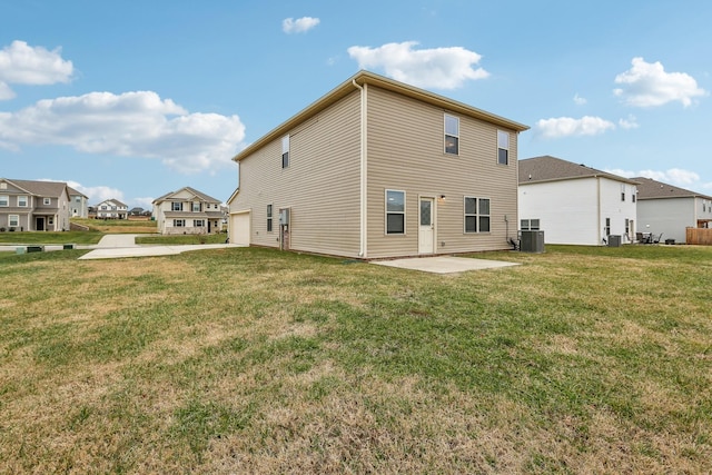 rear view of property with a garage, a yard, a patio, and central AC