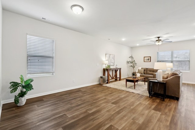 living room featuring ceiling fan and dark wood-type flooring