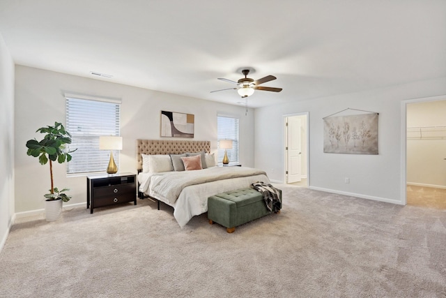 carpeted bedroom featuring ceiling fan, a walk in closet, and a closet