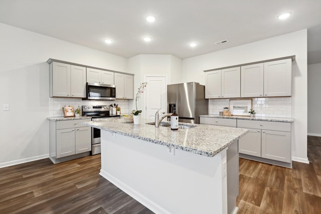 kitchen with gray cabinets, sink, stainless steel appliances, and an island with sink