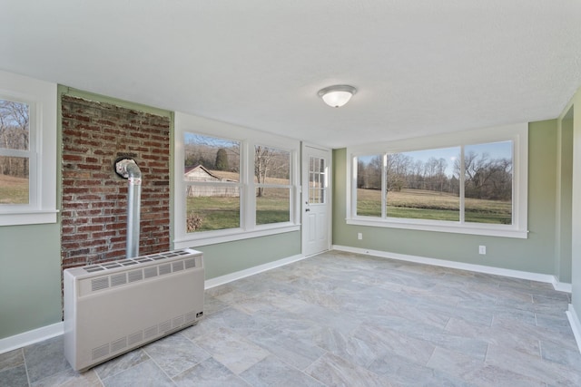 unfurnished sunroom featuring radiator and plenty of natural light