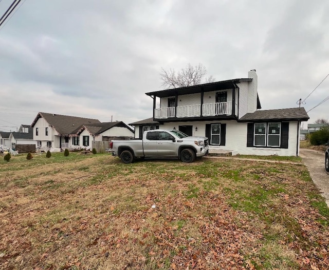 view of front of home with a balcony and a front yard