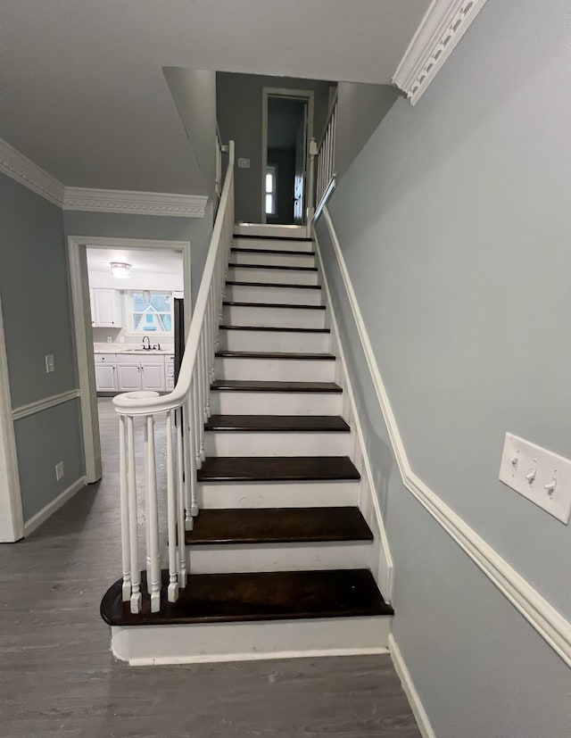 stairs featuring sink, hardwood / wood-style floors, and ornamental molding