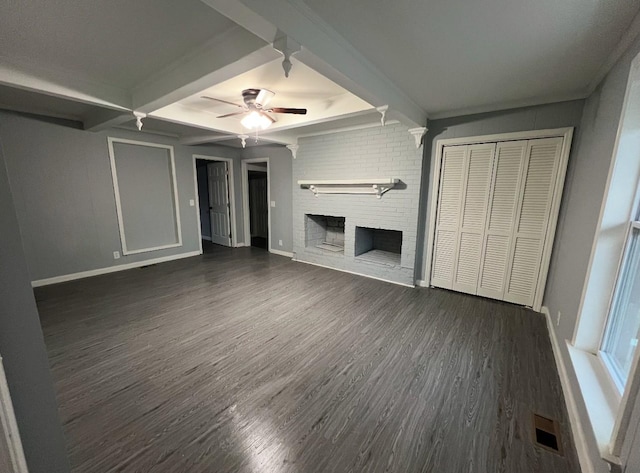 unfurnished living room with beam ceiling, ceiling fan, dark hardwood / wood-style floors, and a brick fireplace