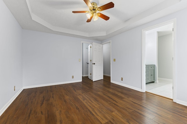 unfurnished bedroom with a raised ceiling, ceiling fan, dark hardwood / wood-style flooring, and ensuite bathroom