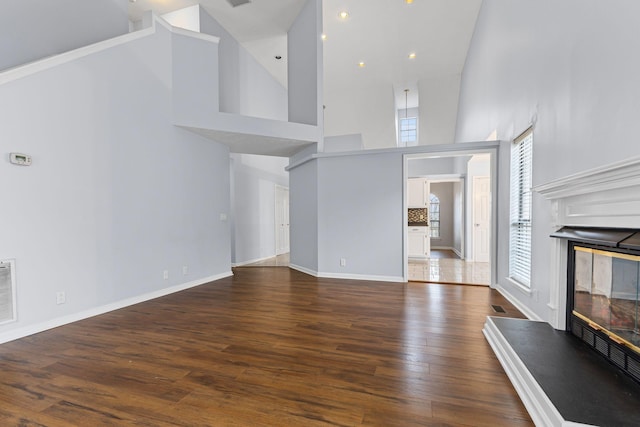 unfurnished living room with high vaulted ceiling and dark wood-type flooring