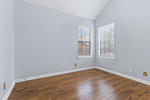 empty room with dark wood-type flooring and lofted ceiling