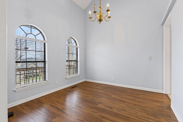 spare room with dark hardwood / wood-style flooring, high vaulted ceiling, and a chandelier