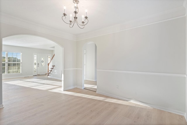 empty room featuring light wood-type flooring, an inviting chandelier, and crown molding