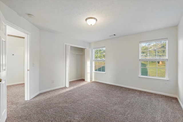 unfurnished bedroom with carpet, a textured ceiling, and a closet