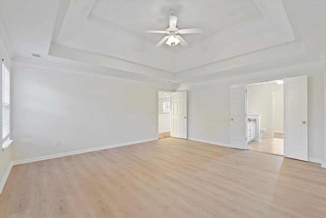 unfurnished room featuring light hardwood / wood-style floors, a raised ceiling, and ceiling fan