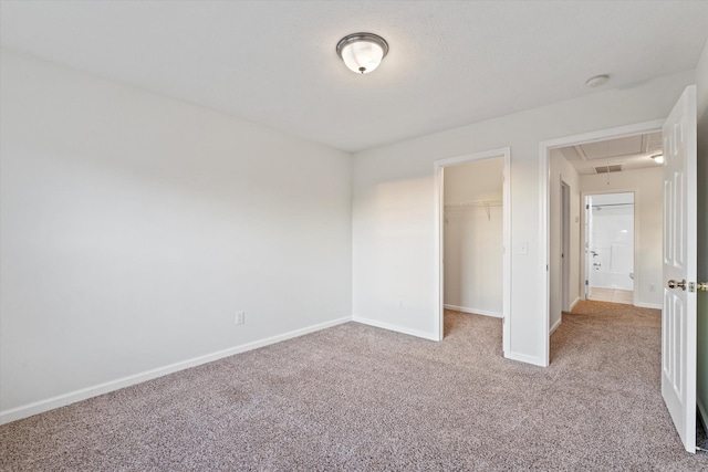 unfurnished bedroom featuring a walk in closet, light colored carpet, and a closet