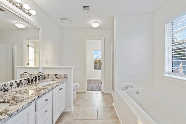 bathroom featuring tile patterned floors, vanity, a relaxing tiled tub, and toilet