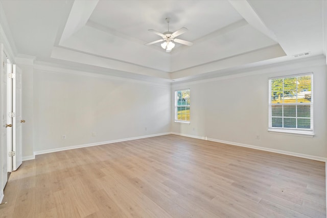 empty room with ceiling fan, ornamental molding, light hardwood / wood-style flooring, and a tray ceiling