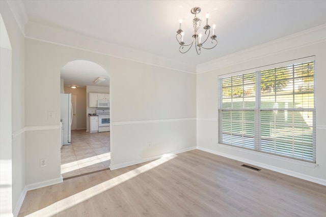 empty room featuring a chandelier, light hardwood / wood-style flooring, and crown molding