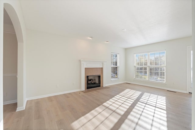 unfurnished living room featuring a tiled fireplace and light wood-type flooring