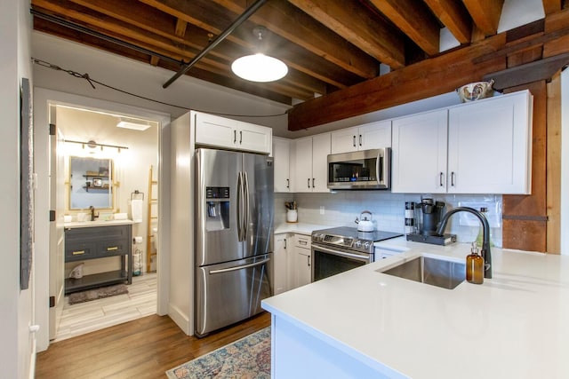 kitchen with decorative backsplash, appliances with stainless steel finishes, light wood-type flooring, sink, and white cabinets