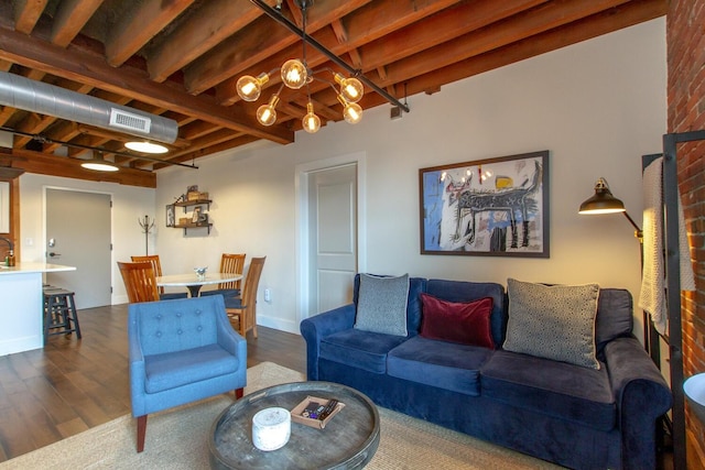 living room featuring beam ceiling, dark wood-type flooring, and a notable chandelier