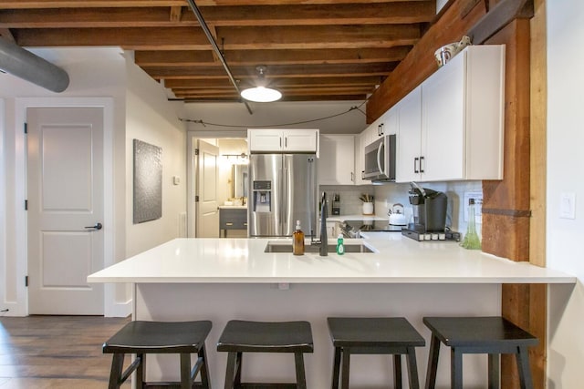 kitchen with a breakfast bar, white cabinets, appliances with stainless steel finishes, tasteful backsplash, and kitchen peninsula