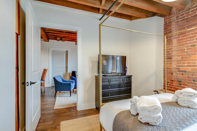 bedroom with beamed ceiling, hardwood / wood-style floors, and brick wall