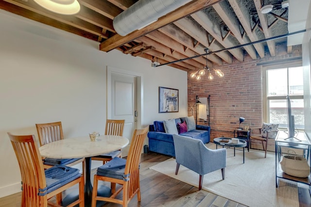 dining room featuring a chandelier, hardwood / wood-style flooring, and brick wall