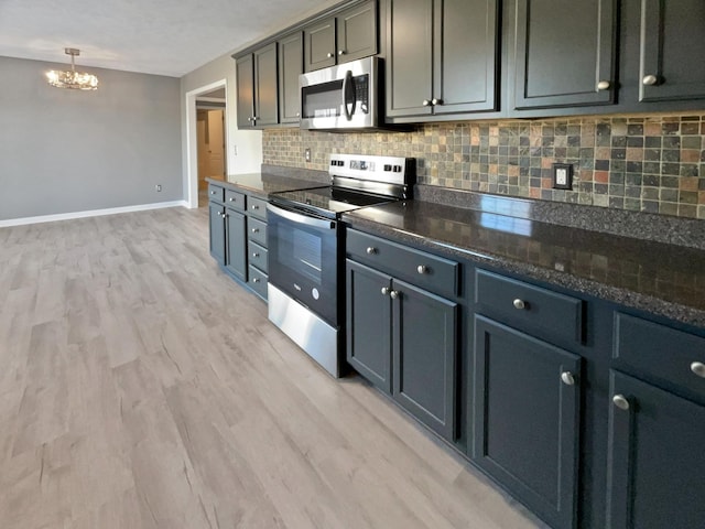 kitchen with hanging light fixtures, tasteful backsplash, light hardwood / wood-style flooring, dark stone countertops, and appliances with stainless steel finishes