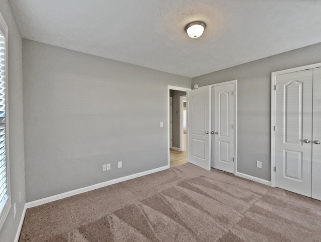 unfurnished bedroom with light colored carpet and two closets