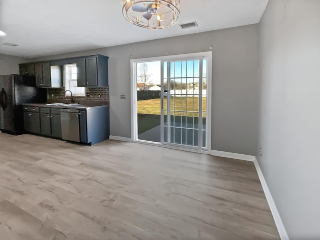 kitchen featuring sink, tasteful backsplash, light hardwood / wood-style flooring, stainless steel dishwasher, and black refrigerator