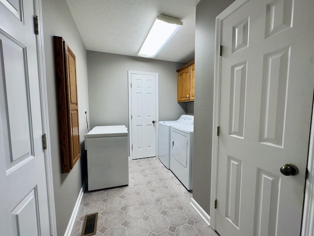 laundry area with washer and dryer, cabinets, and a textured ceiling