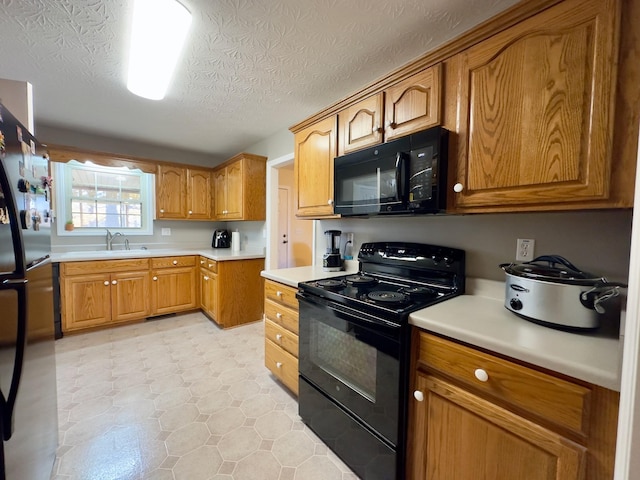 kitchen featuring black appliances, sink, and a textured ceiling