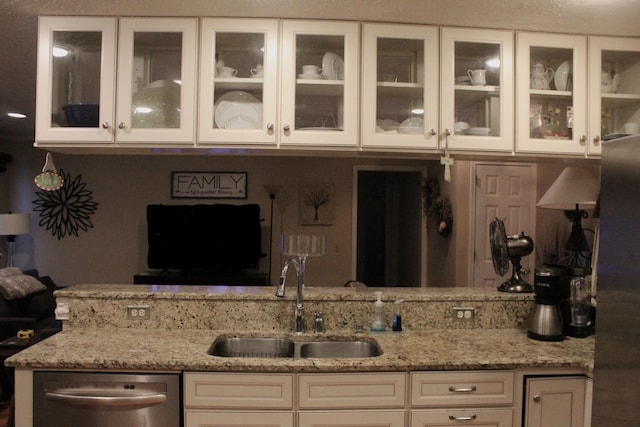 kitchen featuring white cabinets, dishwasher, light stone counters, and sink