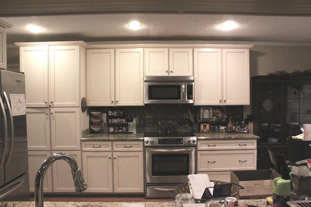 kitchen with dark stone counters, white cabinetry, appliances with stainless steel finishes, and tasteful backsplash