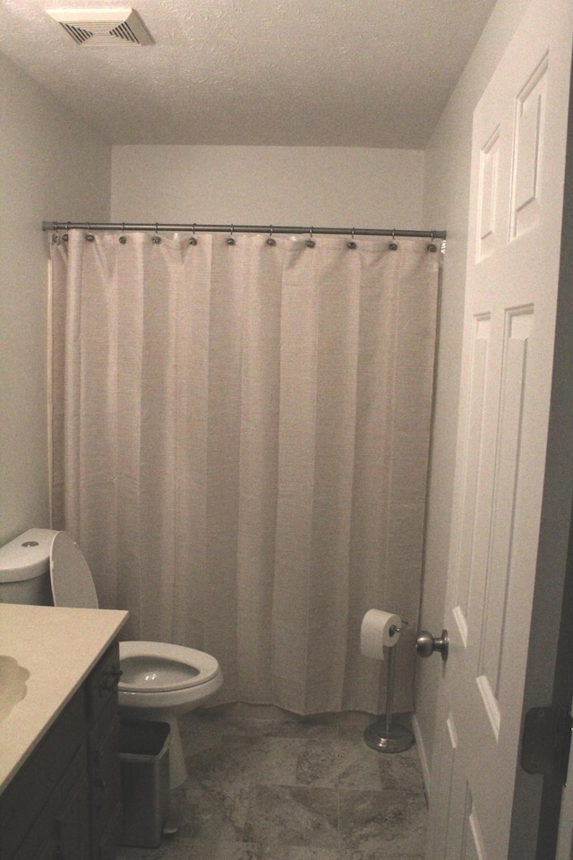 bathroom featuring vanity, toilet, and a textured ceiling