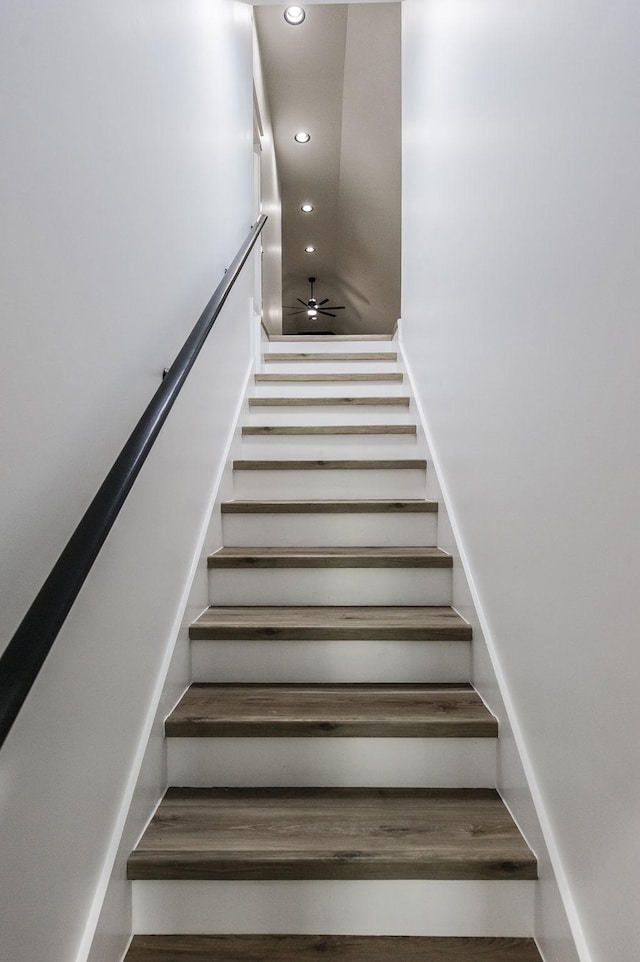 stairway featuring ceiling fan