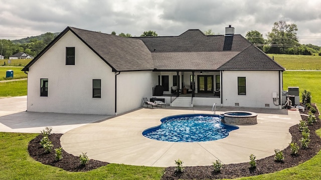 rear view of property with a yard, a swimming pool with hot tub, and a patio area