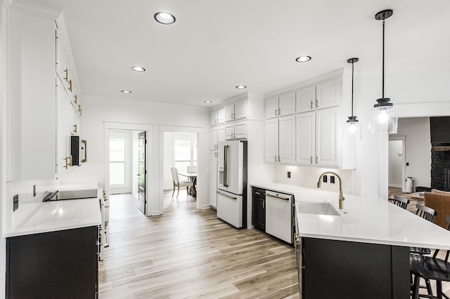 kitchen featuring white appliances, light hardwood / wood-style floors, hanging light fixtures, white cabinets, and sink