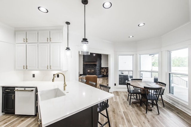 kitchen with white cabinets, pendant lighting, a brick fireplace, and sink