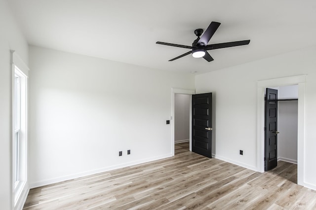 unfurnished bedroom with a closet, ceiling fan, light hardwood / wood-style floors, and a spacious closet