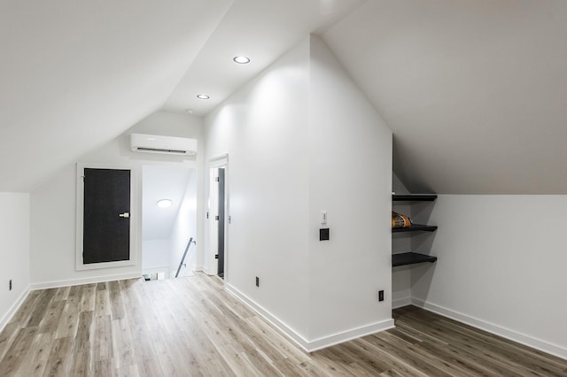 additional living space featuring wood-type flooring, lofted ceiling, and an AC wall unit