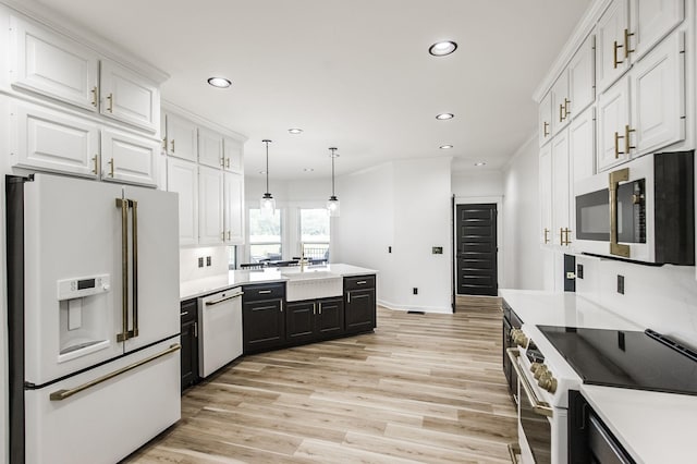 kitchen with white appliances, hanging light fixtures, light hardwood / wood-style flooring, and white cabinets